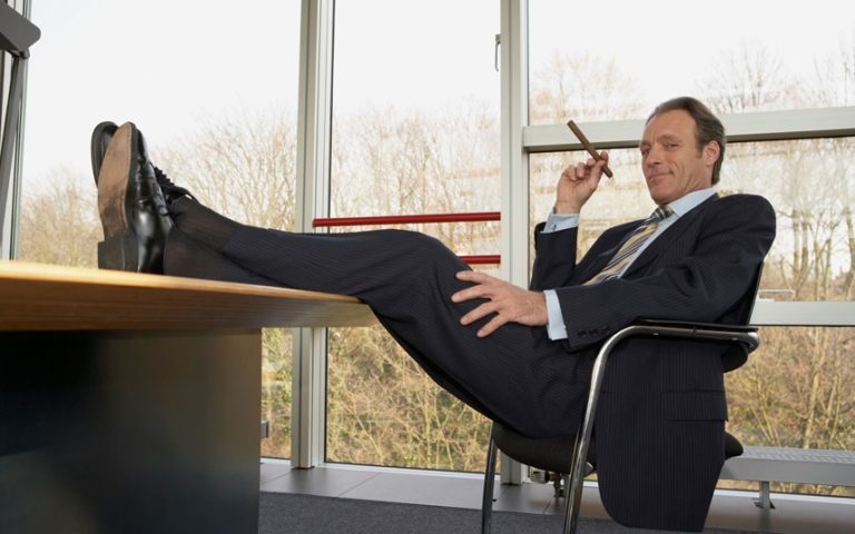 The image shows a businessman seated in an office chair.