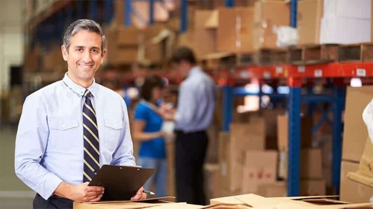The image depicts a warehouse manager inspecting boxes.