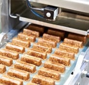 The image depicts the production of confectionery items on a conveyor belt.