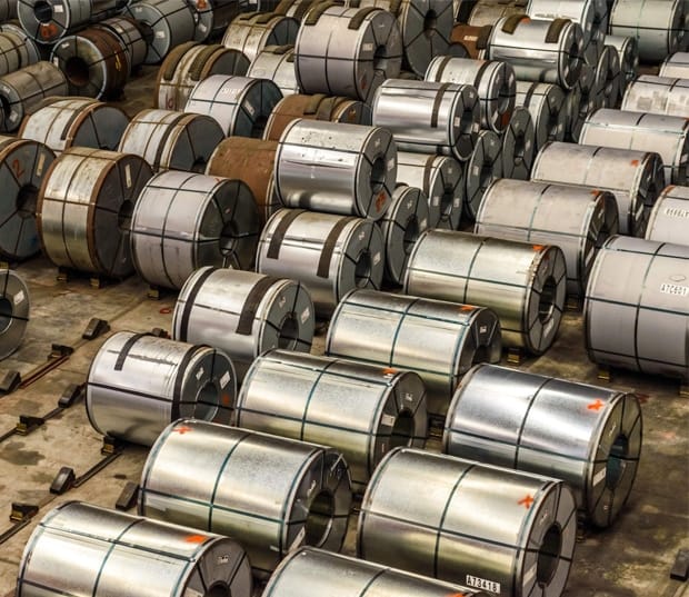 Rows of coiled metal sheets stacked neatly inside a storage facility, showcasing industrial materials
